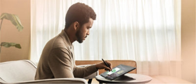 A man sitting at a table using a stylus.