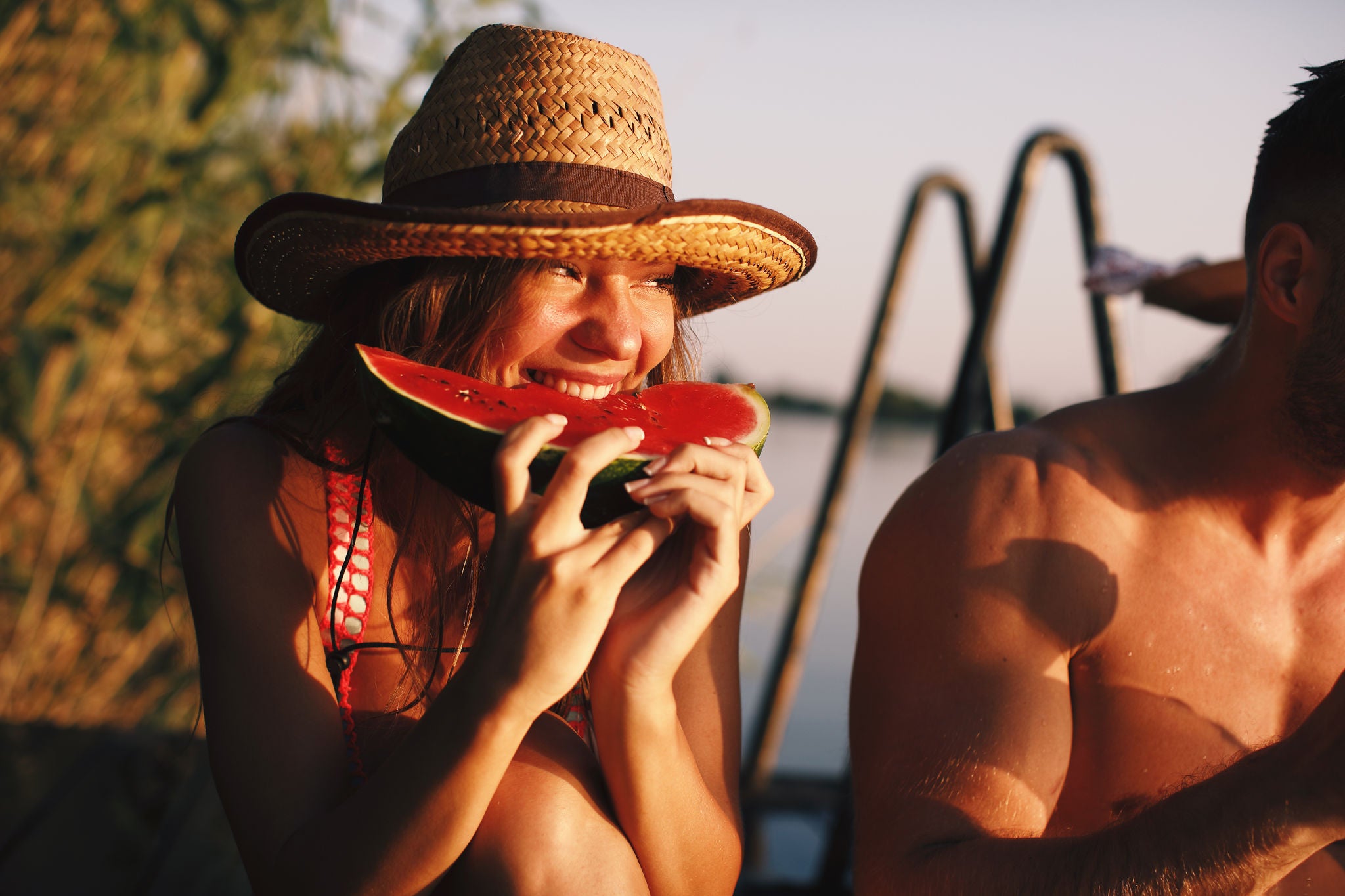Junge attraktive Frau und Mann essen Wassermelone an einem sonnigen Sommertag