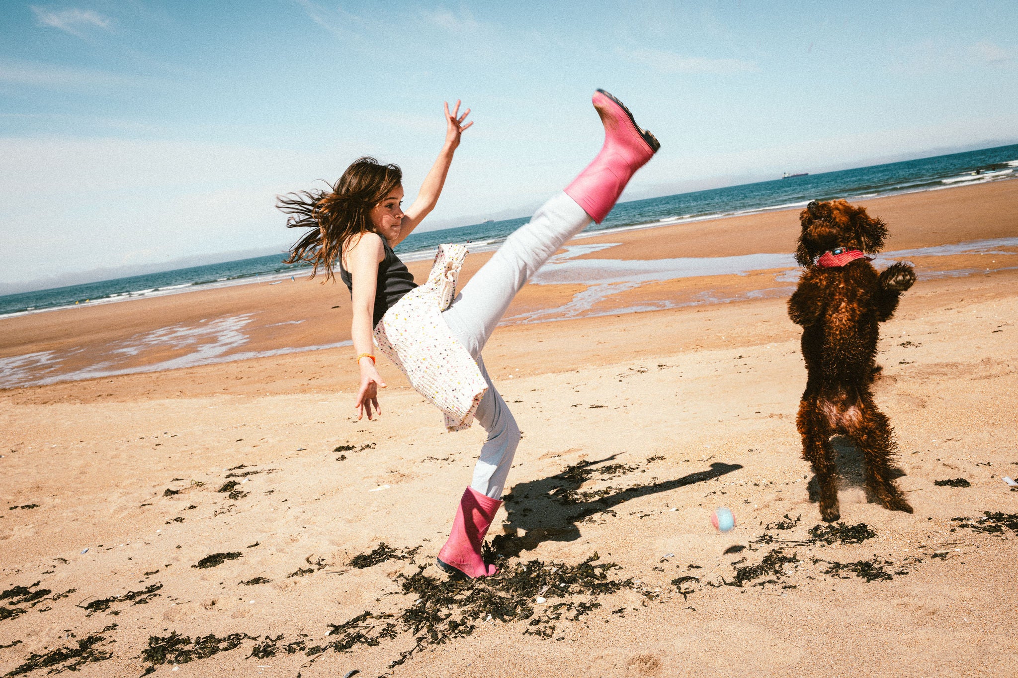 Mädchen beim Ballspielen mit Hund am Strand