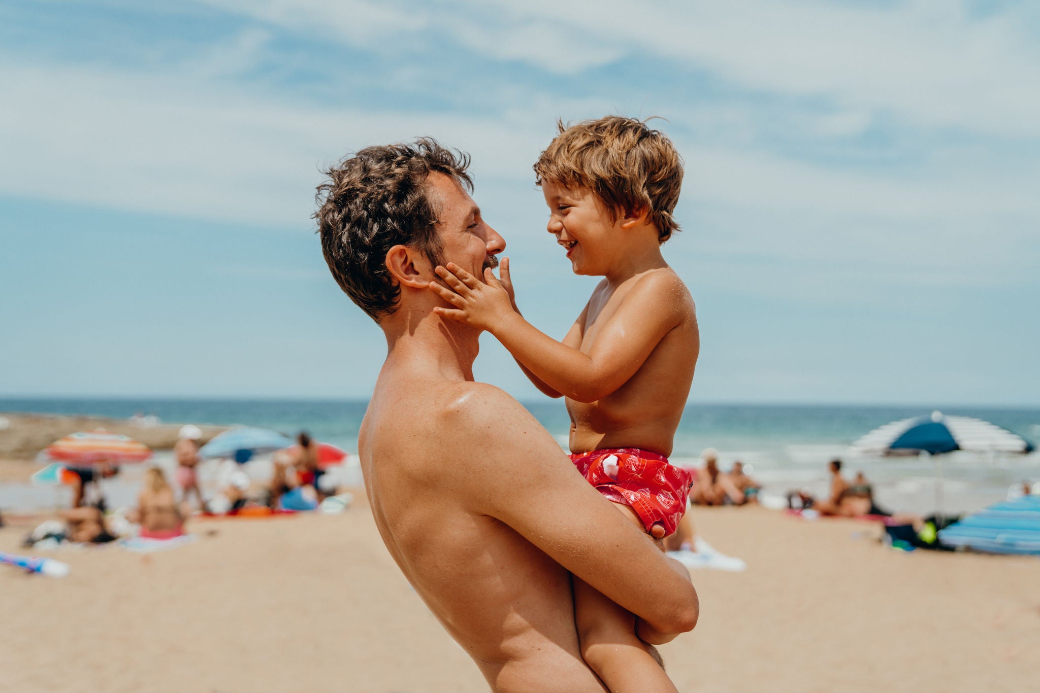 Junge spielt mit seinem Vater am Strand